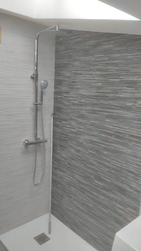 Ducha con columna termostática, plato blanco y revestimiento gris veteado